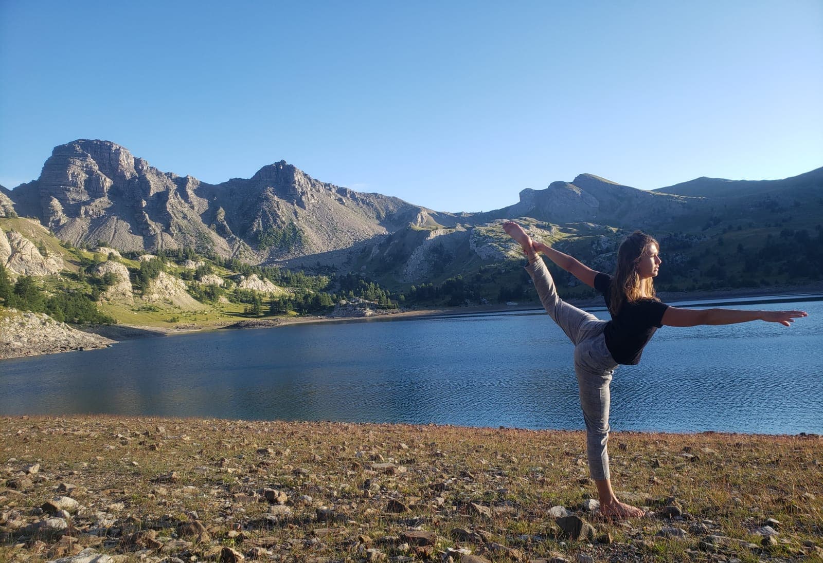 Noémie en posture de yoga au bord d'un lac de montagne
